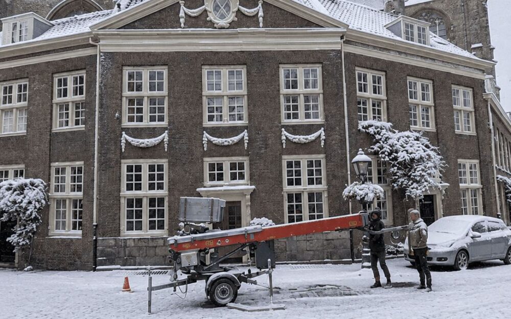 Historic Alkmaar square covered in snow with the Grote Kerk tower visible behind period buildings