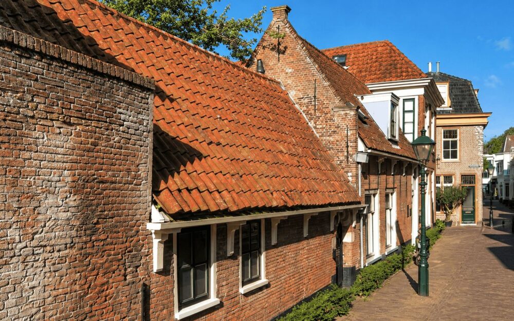 Traditional brick houses with red-tiled roofs on a quiet historic Dutch street corner