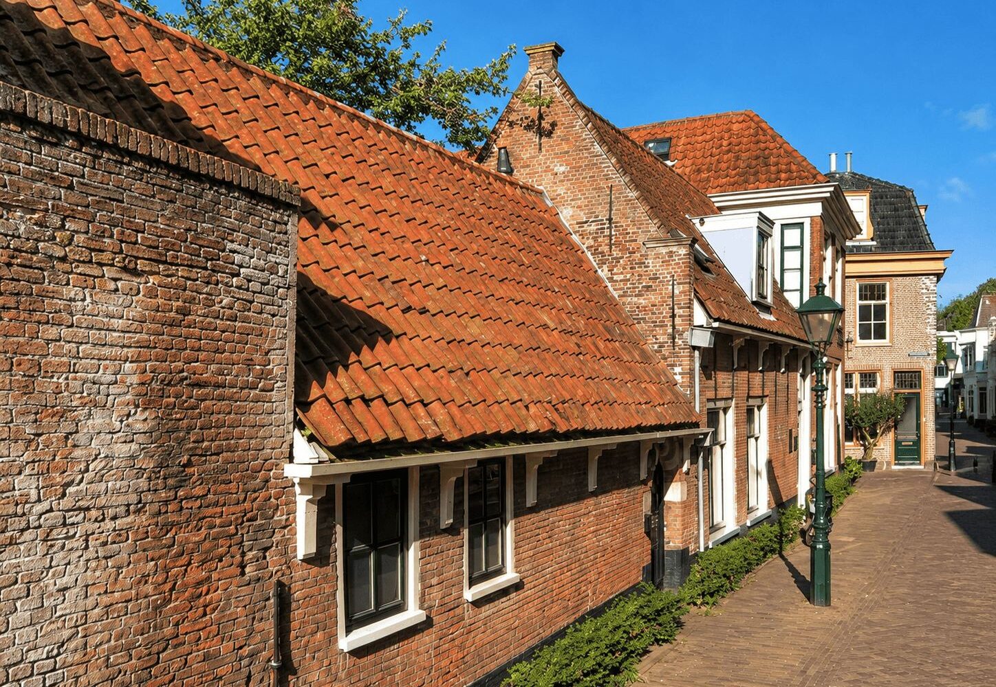 Traditional brick houses with red-tiled roofs on a quiet historic Dutch street corner