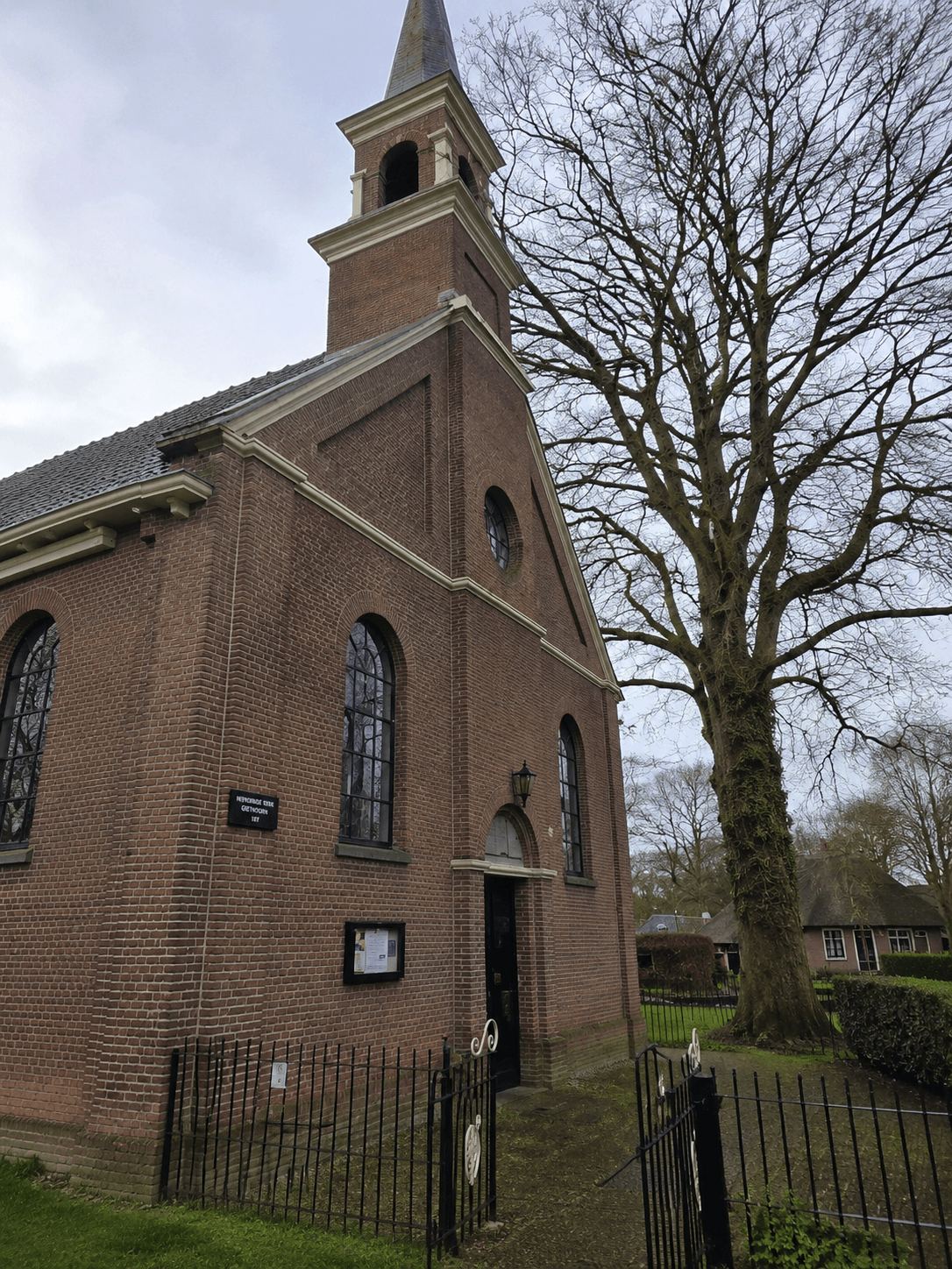 Brick church with a tall spire in Giethoorn photographed in winter with bare trees