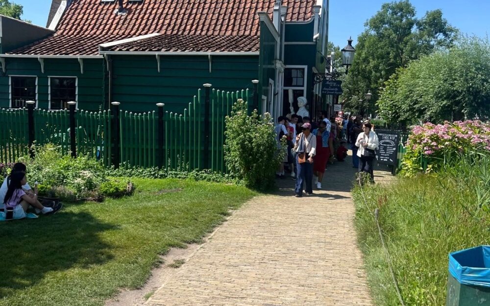 Family walking along a path between green wooden buildings at Zaanse Schans