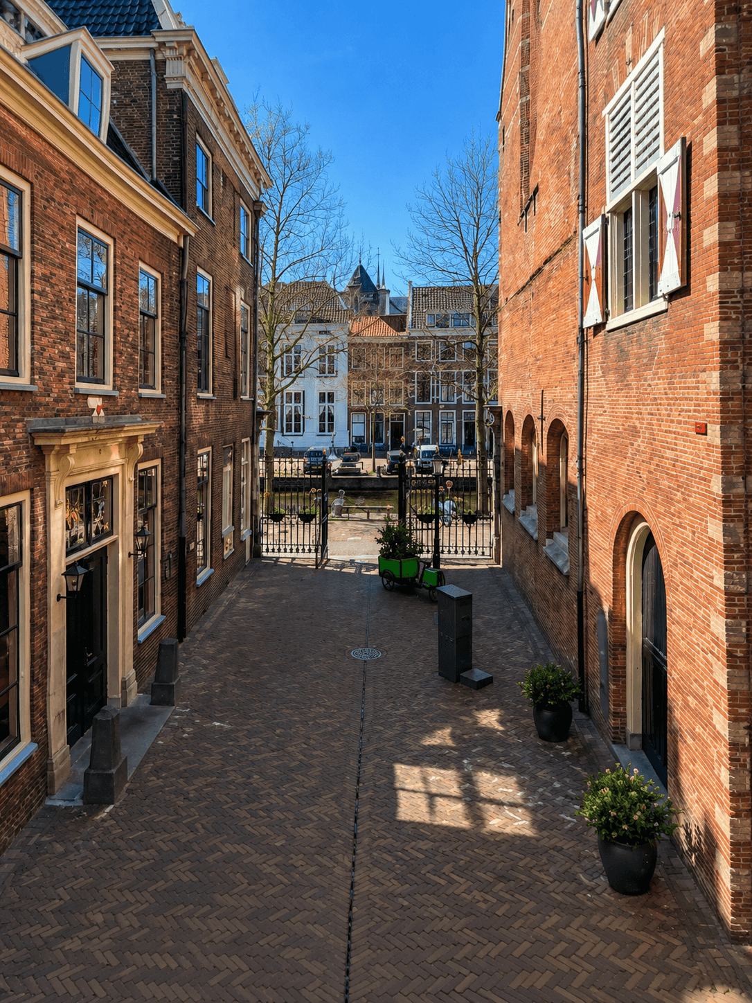 A Quiet Alley Leading to a Leiden Canal Narrow brick alley between historic buildings leading toward a Leiden canal