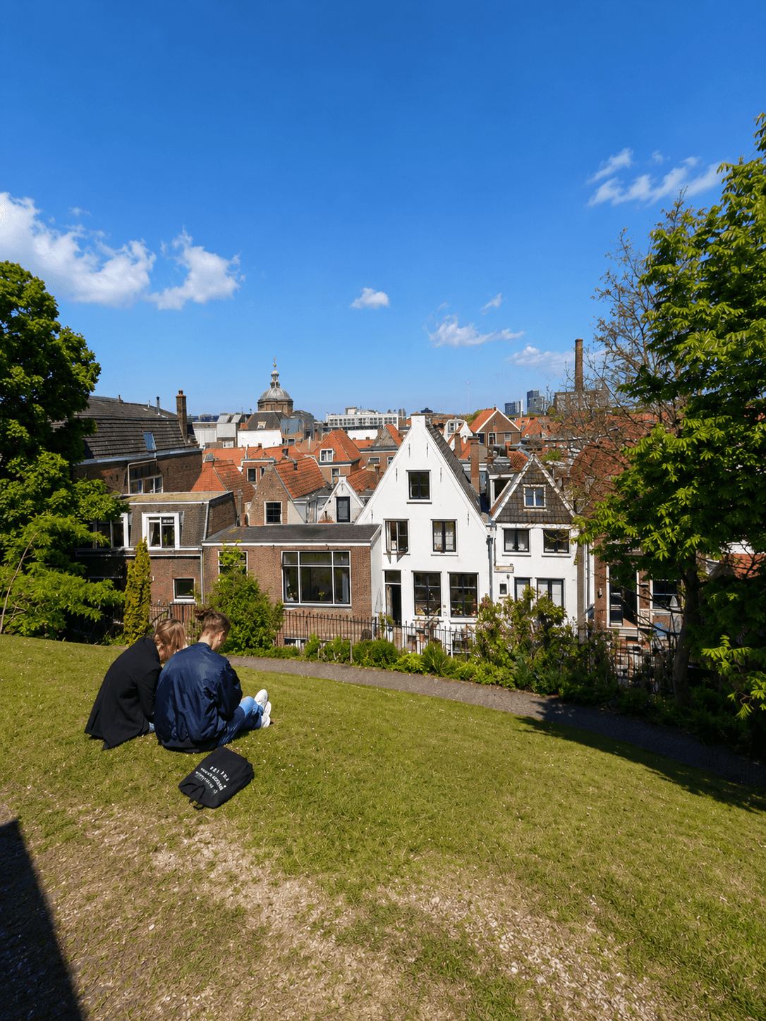 Sitting on the Burcht Mound Above Leiden Two visitors sitting on the grass of the Burcht van Leiden mound overlooking the city rooftops