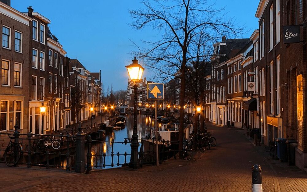 Leiden canal street lit by lamplight at dusk with reflections in the water