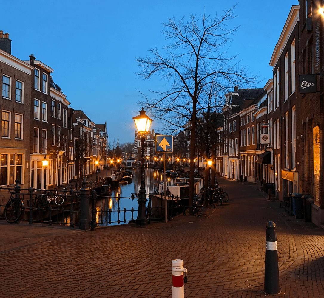Leiden canal street lit by lamplight at dusk with reflections in the water