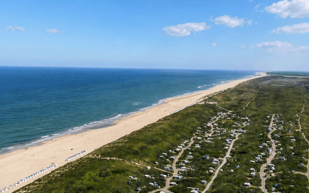 Aerial view of a wide sandy Texel beach next to a holiday park nestled in the dunes